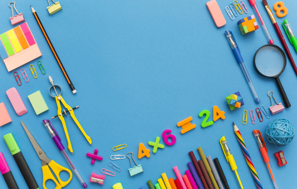 Много разных канцелярских предметов на голубом столе