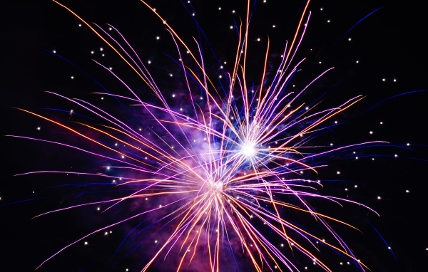 Разноцветные сиреневые искры фейерверка на черном фоне