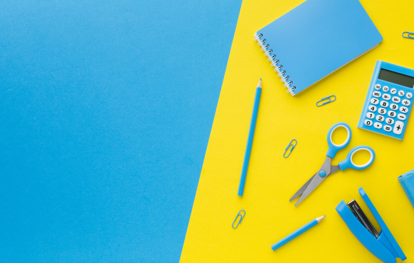 Блокнот, степлер, калькулятор, карандаш и ножницы на голубо-желтом фоне