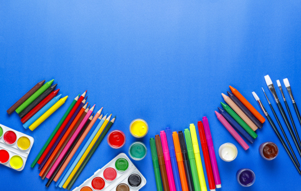 Карандаши, краски, фломастеры и кисти на голубом фоне