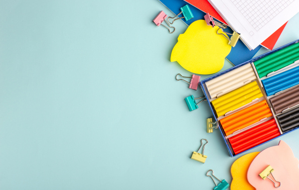 Пластилин на голубом фоне со скрепками и блокнотами