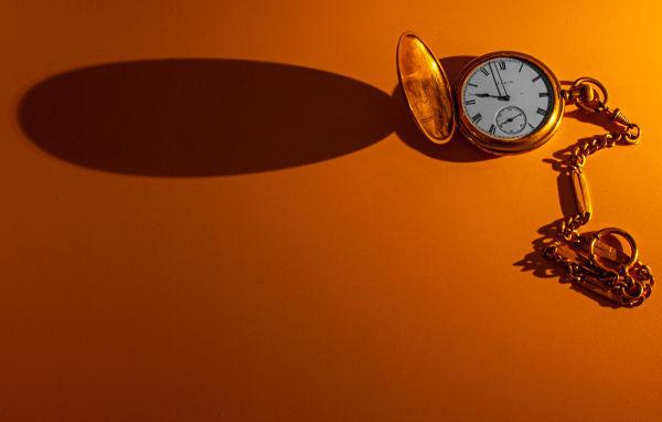 Тень от карманных часов на оранжевом фоне