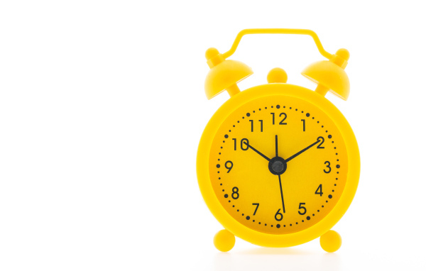 Желтый будильник на белом фоне