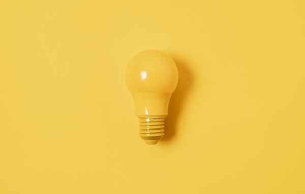 Желтая лампочка накаливания на желтом фоне