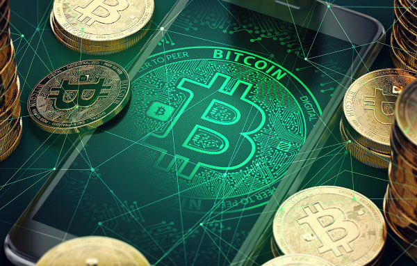 Золотые монеты биткоин со смартфоном на столе