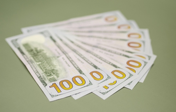 Пачка стодолларовых купюр на зеленом фоне