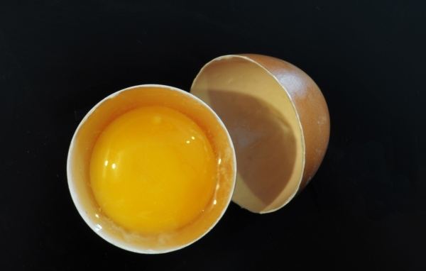 Разбитое яйцо с желтком на черном фоне