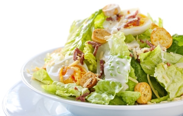 Салат Цезарь на большой белой тарелке