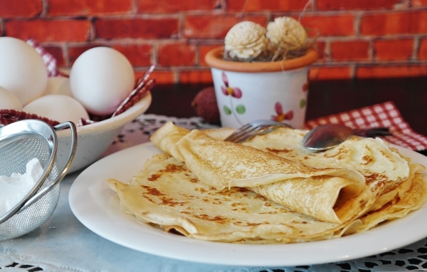 Delicious thin pancakes on the table with eggs
