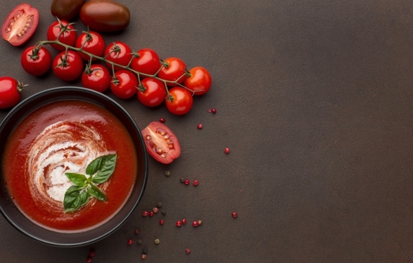 Кетчуп в тарелке на столе с помидорами