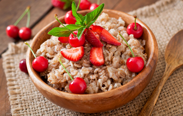 Овсяная каша с ягодами в деревянной миске