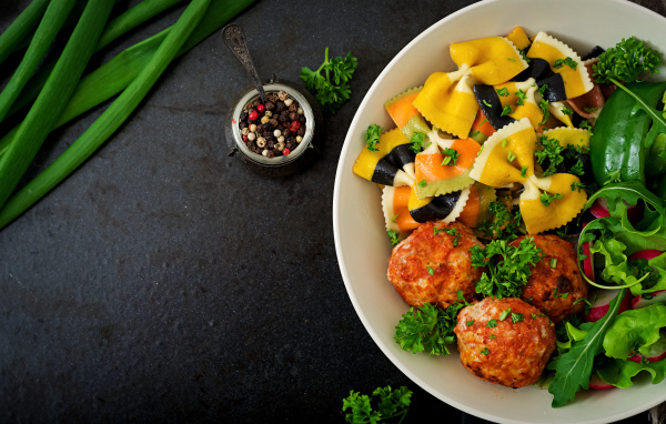 Паста с тефтелями и салатом в тарелке