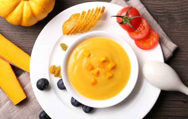 Тыквенный суп пюре на тарелке с картофелем и помидором