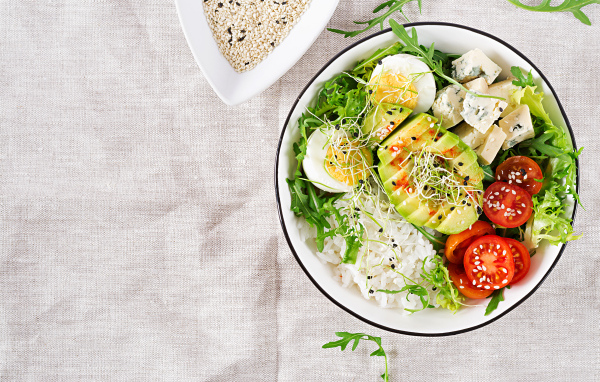 Рис с овощами и авокадо в тарелке