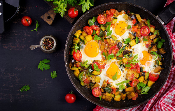 Яичница с овощами в сковороде на столе