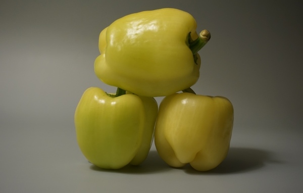 Три желтых перца на сером фоне