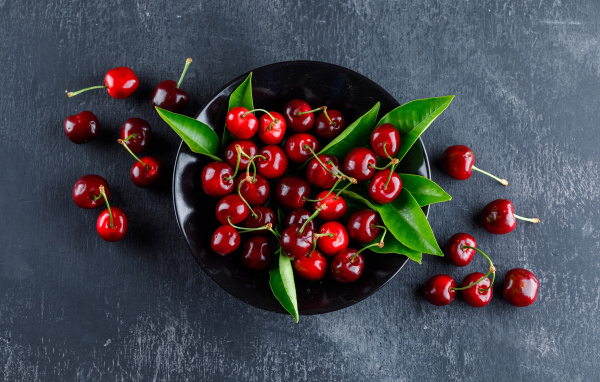Черная  тарелка с красными ягодами черешни