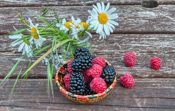 Ягоды черники и малины на столе с ромашками