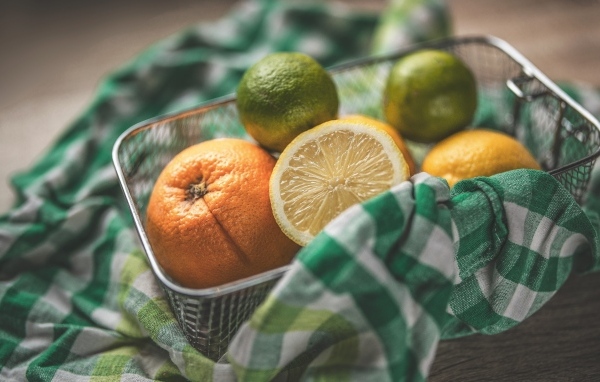 Цитрусовые фрукты в железной корзинке на столе