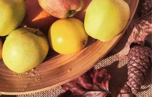 Чистые спелые яблоки на столе с шишкой