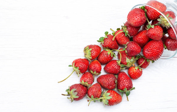 Стеклянный стакан с ягодами клубники на столе