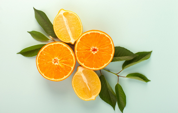 Половинки лимона и апельсина на столе с зелеными листьями