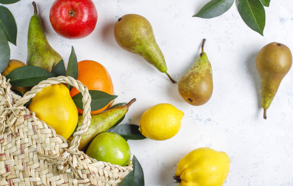 Груши, яблоки и апельсины с сумкой на столе