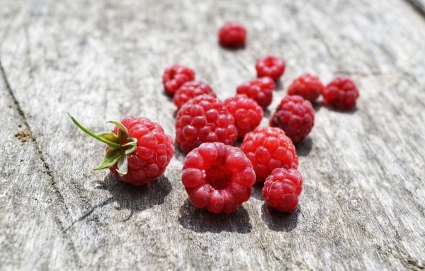 Красные ягоды малины на деревянном столе