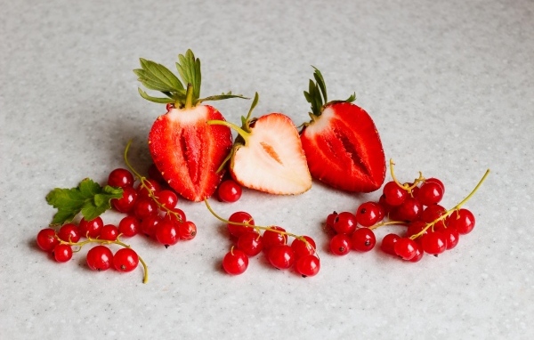 Ягоды клубники с красной смородиной на сером столе