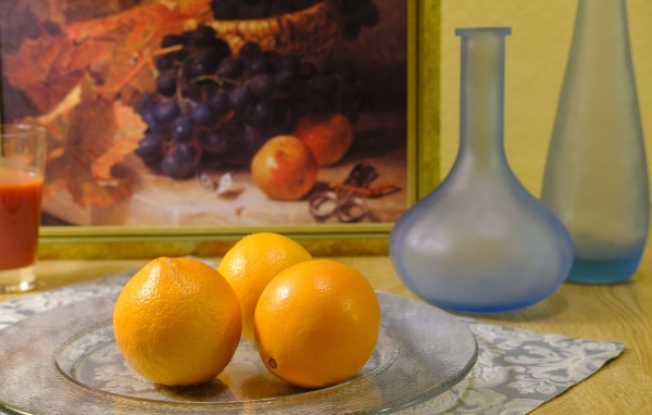 Три апельсина с вазами на столе