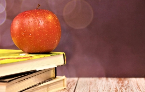 Мокрое яблоко на столе с книгами