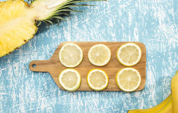 Деревянная доска с лимоном на столе с ананасом