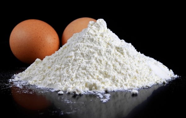 Мука на черном столе с куриными яйцами