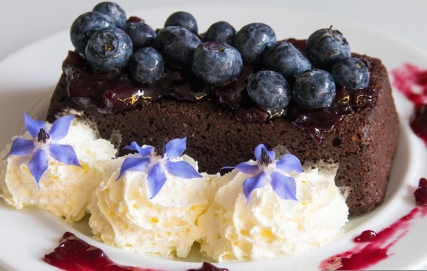 Шоколадный торт с черникой на тарелке со взбитыми сливками