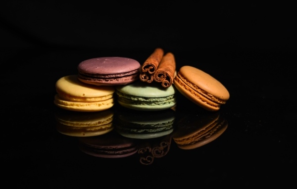 Десерт макарон с корицей на черном фоне