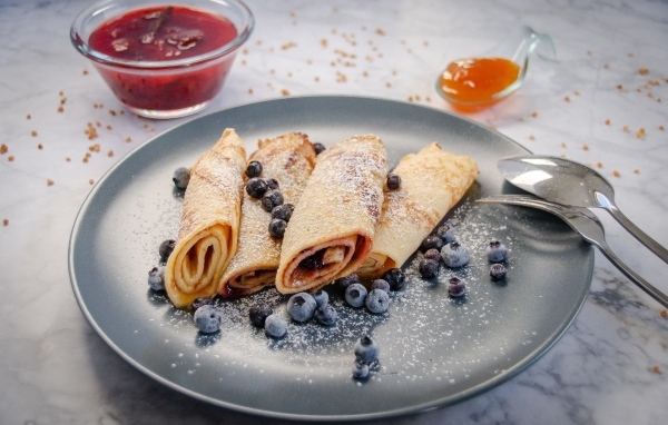 Блинчики с черникой и сахарной пудрой на тарелке на столе