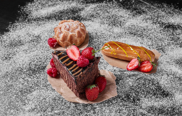 Кусок торта с ягодами на столе с эклером