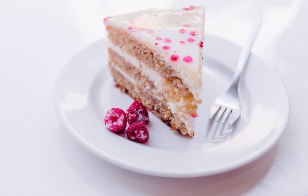 Кусок торта с замороженной малиной на белой тарелке