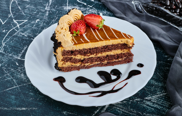 Кусок торта с клубникой на большой белой тарелке