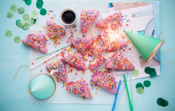 Кусочки торта в розовой глазури на столе с праздничным декором