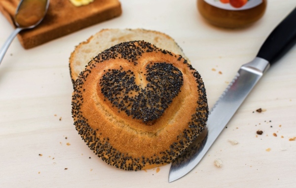 Булочка с маком с нарисованным сердцем на столе