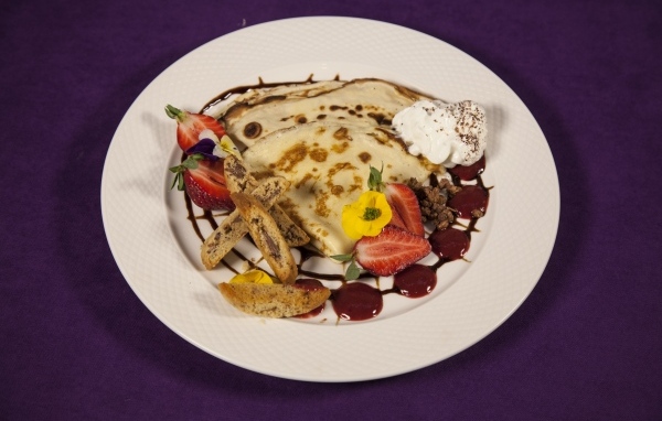 Тонкие блинчики с кремом и ягодами на тарелке