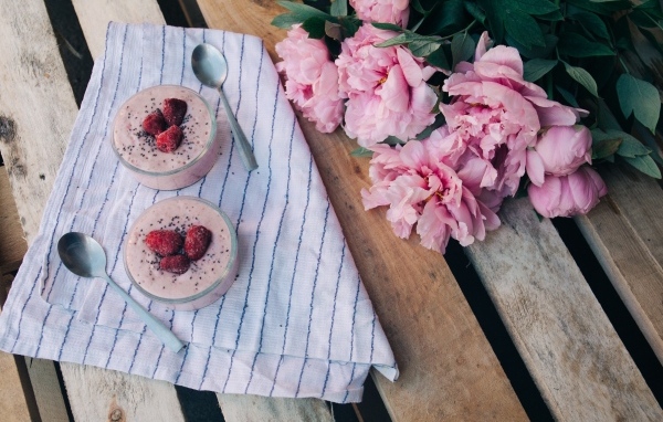 Два стакана с десертом на лавке с букетом пионов