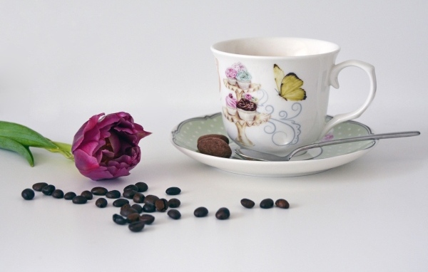 Чашка на столе с кофейными зернами и тюльпаном