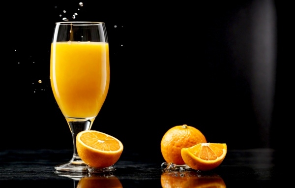 Стакан апельсинового сока с фруктами на столе