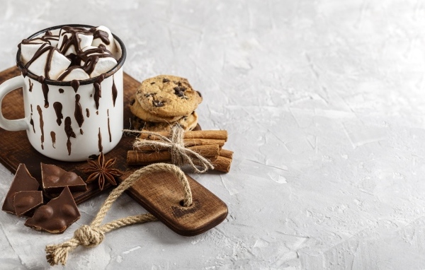 Горячий шоколад с маршмеллоу на столе с печеньем и конфетами