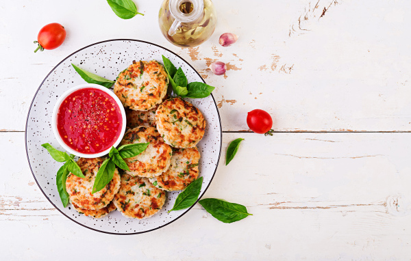 Куриные котлеты на большой белой тарелке  с соусом