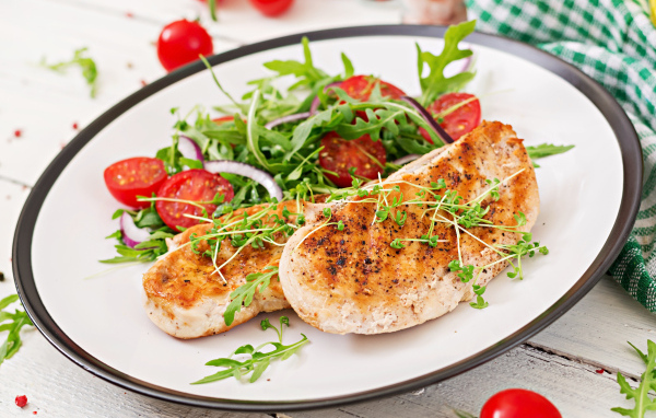 Жареная курица на тарелке с салатом