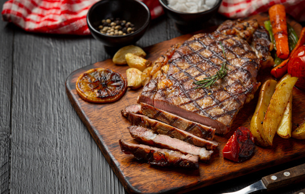 Кусок мясо барбекю на доске с овощами