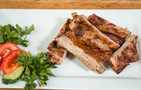 Свиные ребра на тарелке с овощами и зеленью